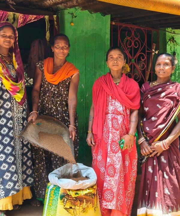 4 tribal women standing in front of a seed bank showing the seeds they have grown and collected